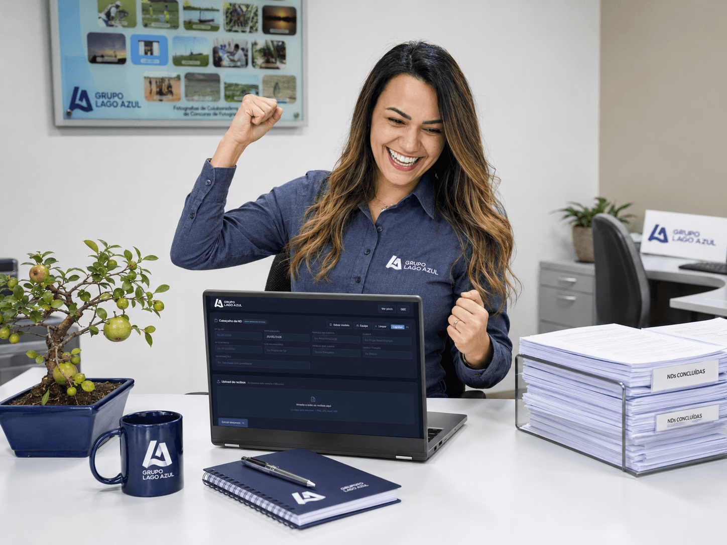 Cátia sorrindo na frente do notebook com o LagoND rodando, agora com um bonsai de goiabeira na mesa.